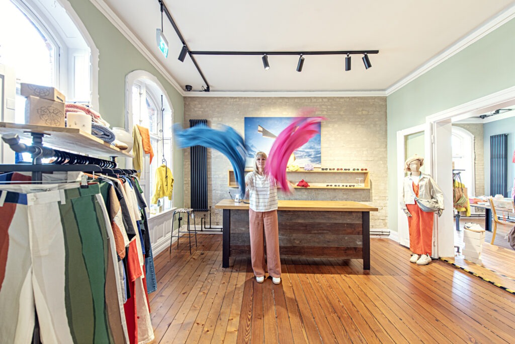 Inhaberin vor der Kasse schwenkt Decken durch die Luft. Links